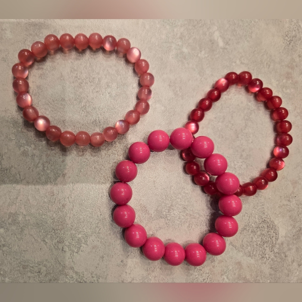 5 pink bracelets, 4 are elastic and one is a resin bangle.